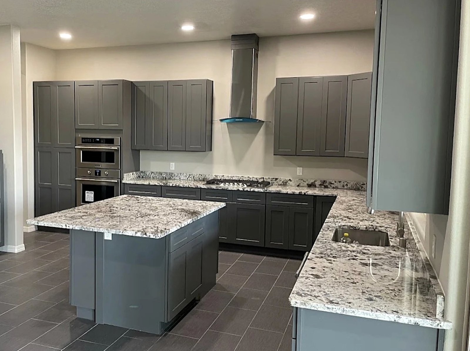 Gray shaker kitchen with granite island and wall ovens
