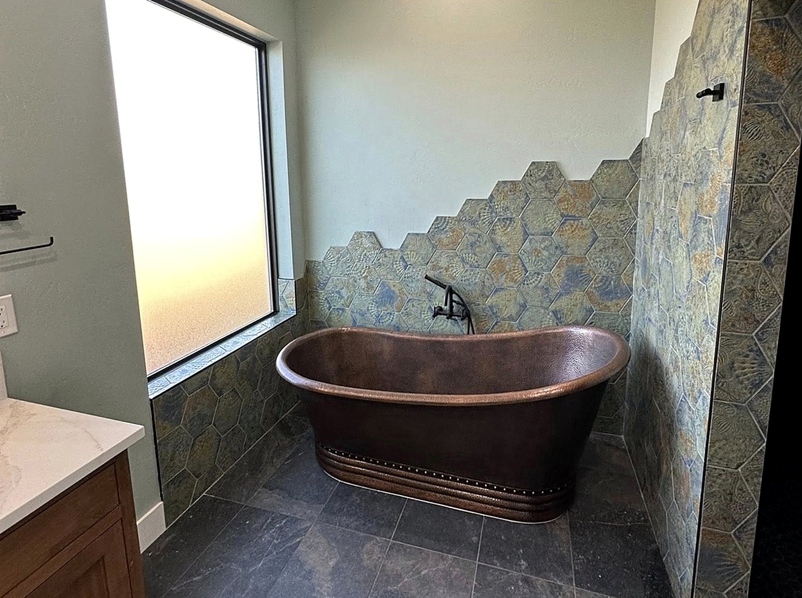 Copper soaking tub with hand-cut hexagon tile