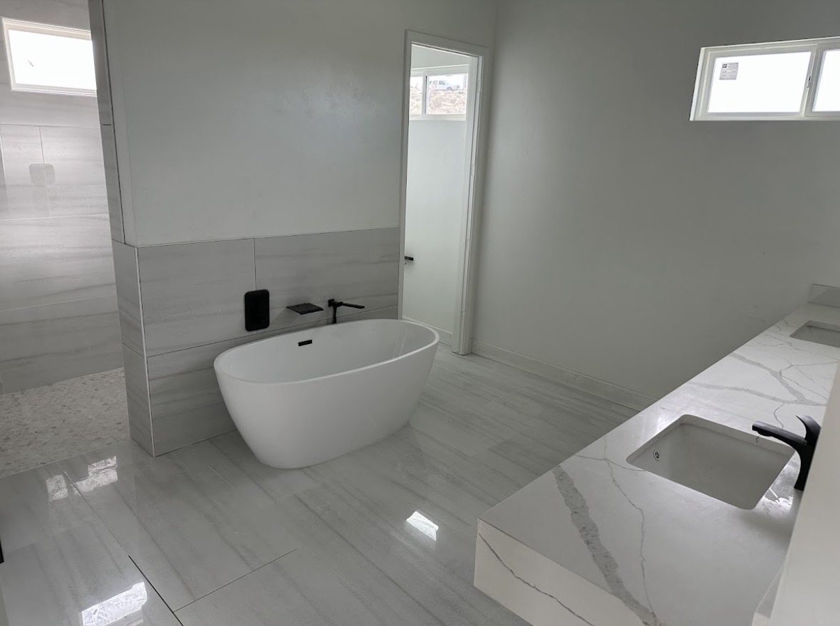 Modern primary bathroom with freestanding tub, walk-in shower, and quartz vanity